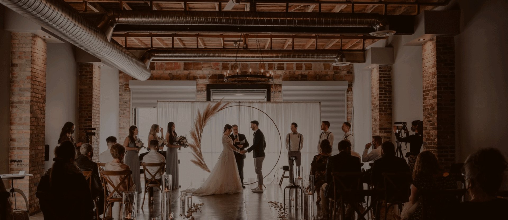 The Glass & Lumber event space in Riversdale, Saskatoon, with exposed brick walls and steel beams set for a wedding reception